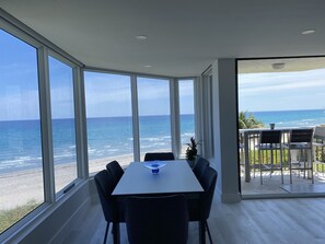 Ein Essbereich mit Meerblick, großen Fenstern und einem Tisch mit Stühlen.