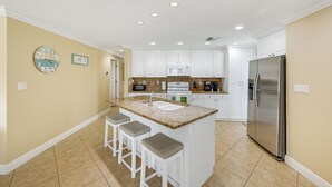 A kitchen with white cabinets, a stainless steel refrigerator, a granite countertop, and a sink. -  **GEM!**3 BR BEACH HOUSE w/ HEATED POOL, short ride to the beach!  (Naples)