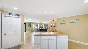 A spacious kitchen with a large island, white cabinetry, and a built-in dishwasher. -  **GEM!**3 BR BEACH HOUSE w/ HEATED POOL, short ride to the beach!  (Naples)