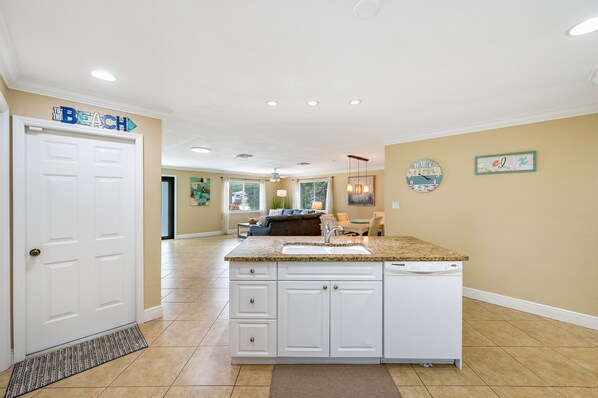 A kitchen with a built-in dishwasher, white cabinetry, and a granite countertop.