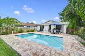 Un patio trasero con piscina, muebles de jardín y cerca de madera.