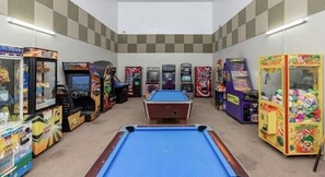 Une salle avec une table de billard, divers jeux d’arcade et des distributeurs automatiques.
