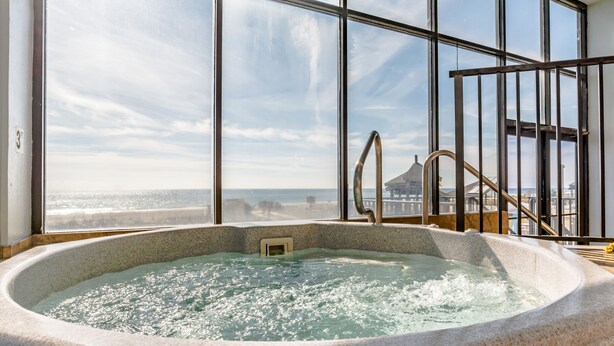 Una bañera de hidromasaje con vista al océano y un edificio al fondo.