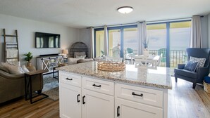 Una sala de estar moderna con una isla de cocina, un comedor y un balcón con vistas.