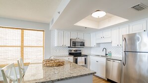 Una cocina moderna con gabinetes blancos, electrodomésticos de acero inoxidable y encimera de granito.