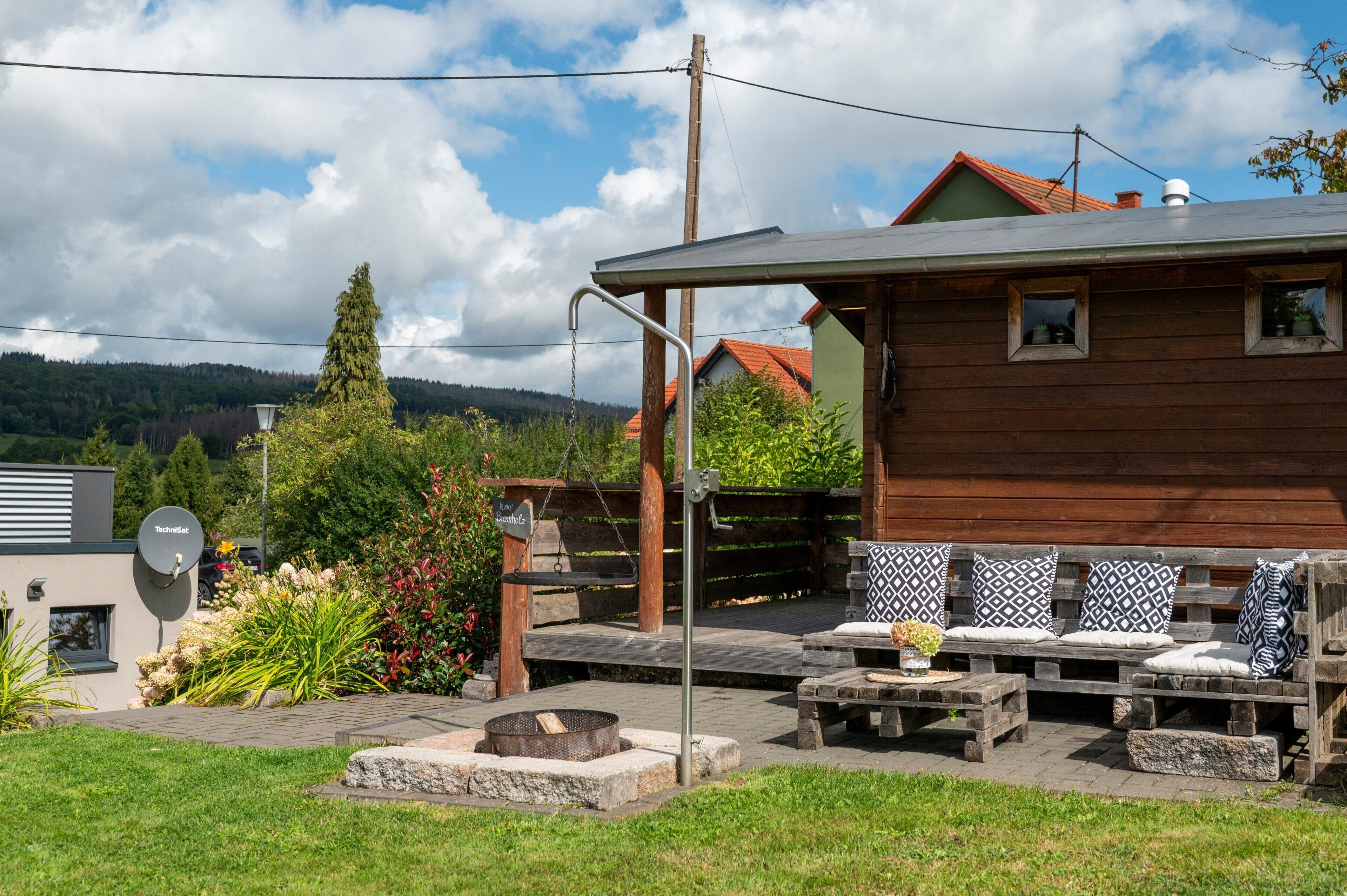 Una casa de madera con un patio, mobiliario exterior y una antena parabólica.