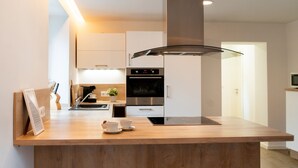 A modern kitchen with a wooden countertop, built-in oven, and stainless steel appliances. - Holiday Home 'Traumzeit' with Private Terrace, Private Garden and Wi-Fi (Neuhütten)
