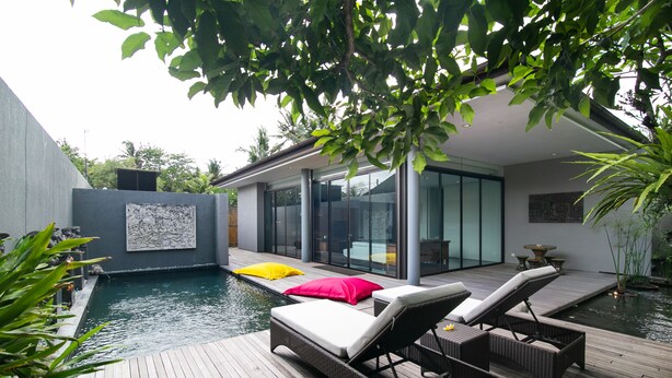 Ein moderner Poolbereich im Freien mit Liegestühlen und einer Holzterrasse.