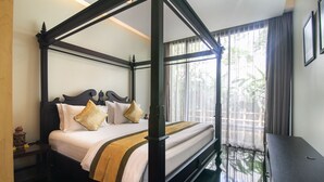 Ein Bett mit Baldachin, mit dunklem Gestell, weißer Bettwäsche und zwei Kissen.
