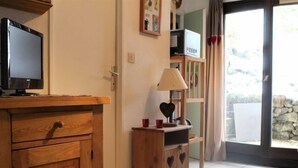 A room with a wooden cabinet, a television, a lamp, and a window with curtains.