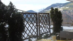 A yellow table with two white cups, a lattice partition, and a snowy mountain view.