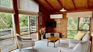 A cozy room with a wooden ceiling, large windows, and a flat-screen TV. - Perfect Waterfront Escape in Marlo | Balcony Views & Nature All Around (Marlo)