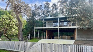 A modern two-story building with a covered outdoor area and a wooden fence in front. - Perfect Waterfront Escape in Marlo | Balcony Views & Nature All Around (Marlo)