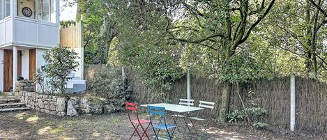 A backyard with a stone wall, a wooden fence, and a table with chairs.