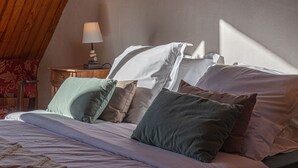 Ein Schlafzimmer mit einem Bett, Kissen, einem Nachttisch mit Lampe und einem Holzstuhl.