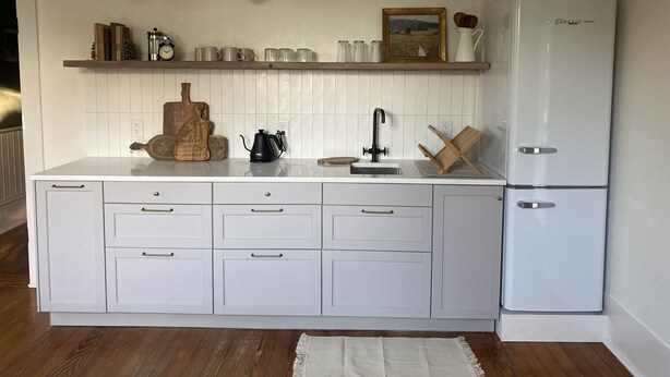 A kitchen with white cabinetry, a white refrigerator, a wooden cutting board, a coffee pot, and a hanging light fixture. - Historic • Hot tub • A&M Ring Day (Bryan)