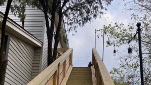 Un escalier en bois mène à un bâtiment à la façade blanche.