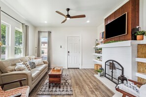 A living room with a sofa, coffee table, and a fireplace. - Stay Downtown Waco! Close to Magnolia, Baylor, Cameron park (Waco)