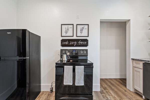 A kitchen with a black refrigerator, a stove, and a sign that says 'cook. sing. dance.' - Stay Downtown Waco! Close to Magnolia, Baylor, Cameron park (Waco)