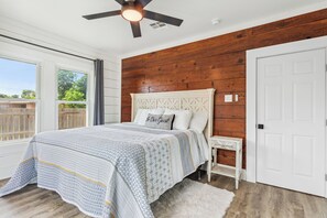 A bedroom with a bed, a nightstand, a ceiling fan, and a view of the outdoors. - Stay Downtown Waco! Close to Magnolia, Baylor, Cameron park (Waco)