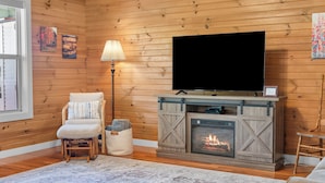 A cozy living room with a fireplace, a television, and a comfortable chair.