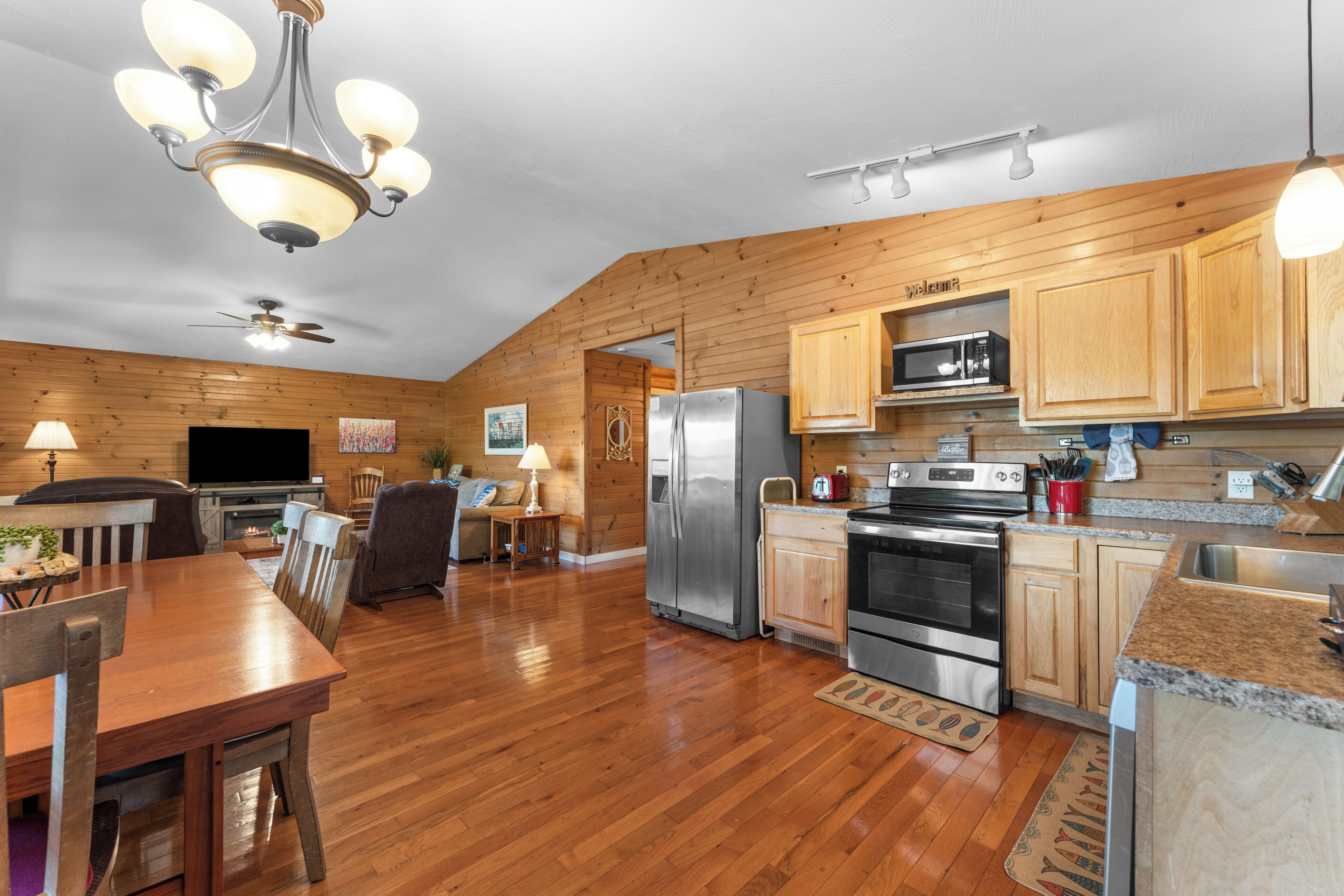 A kitchen with wooden cabinets, a stainless steel refrigerator, a microwave, and a stove.