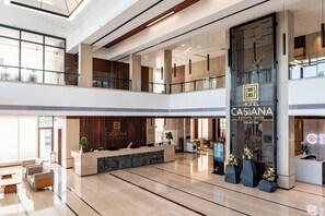 Eine moderne Hotelhalle mit Empfangstresen, Sitzgelegenheiten und einer großen vertikalen Beschilderung für das Casiana Hotel & Events Center.