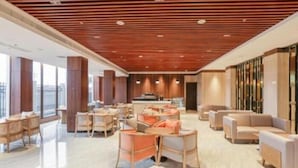 A modern hotel lobby with wooden ceiling panels, large windows, and a mix of seating arrangements including sofas and tables. - Hotel Casiana and Events Center Tagaytay (Tagaytay)