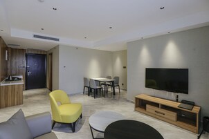 A modern living room with a TV, seating, and a dining area.