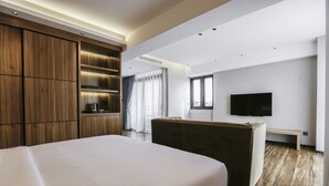 A modern hotel room with a large bed, wooden wardrobe, a flat-screen TV, and a seating area. - Hotel Casiana and Events Center Tagaytay (Tagaytay)