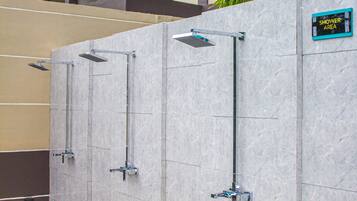 A row of shower cubicles with a sign indicating a shower area, set against a building with multiple floors and balconies.