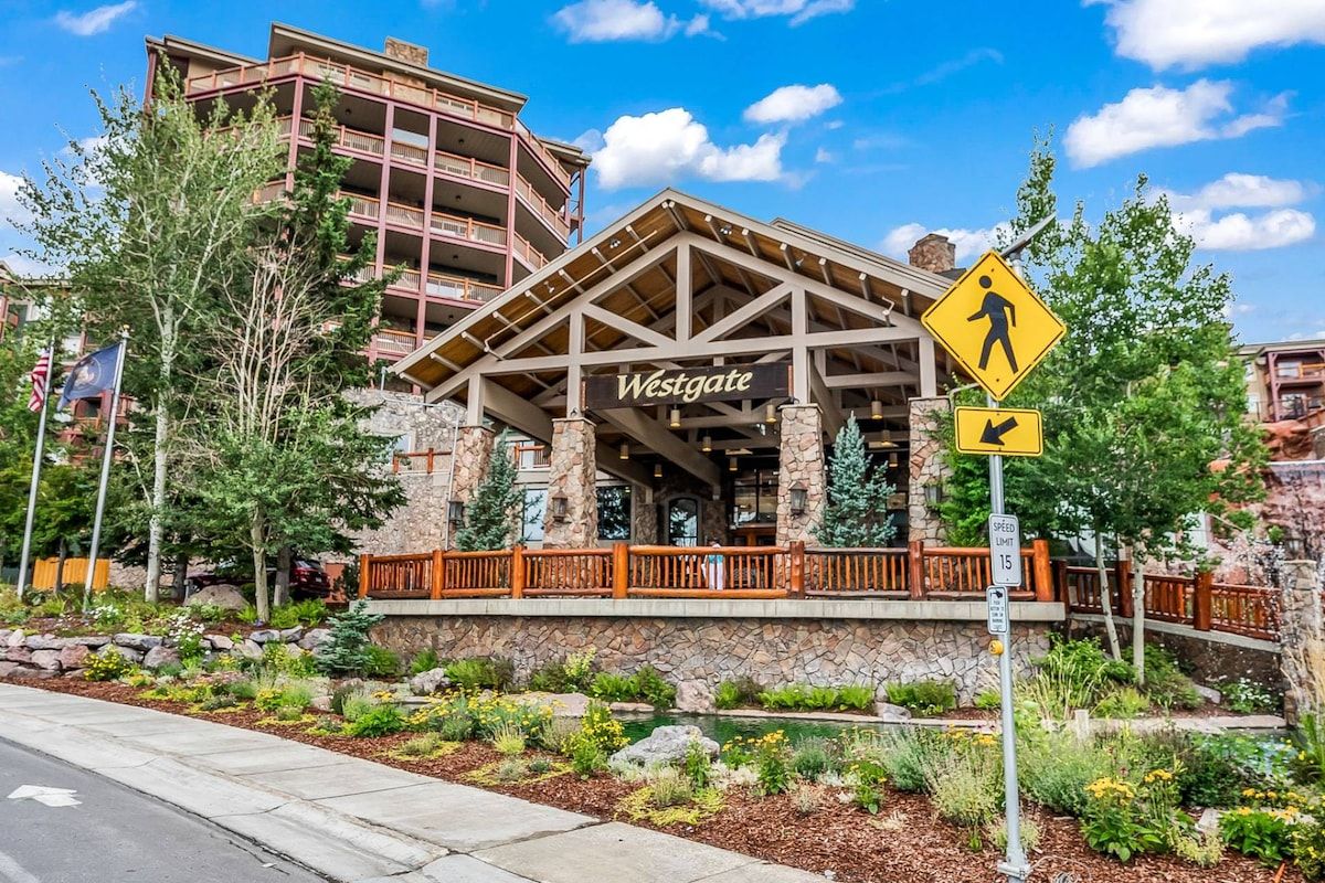 A Westgate hotel with a pedestrian crossing sign, a speed limit sign, and a stone facade.