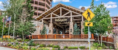 A Westgate hotel with a pedestrian crossing sign, a speed limit sign, and a stone facade.