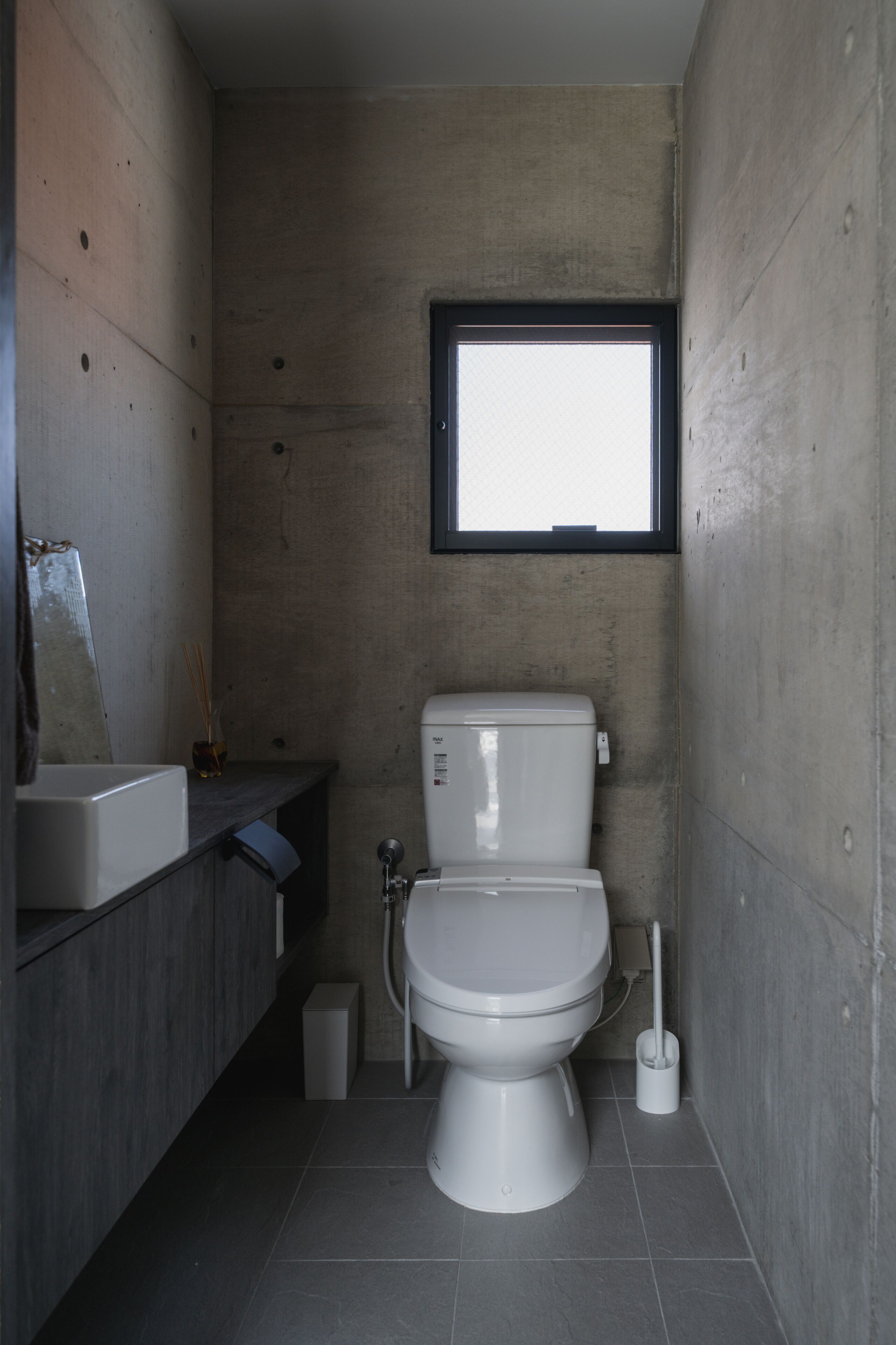 A compact bathroom with a toilet, a small sink, and a window.