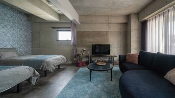 A modern room with two beds, a sofa, a TV, and a small table with a glass.