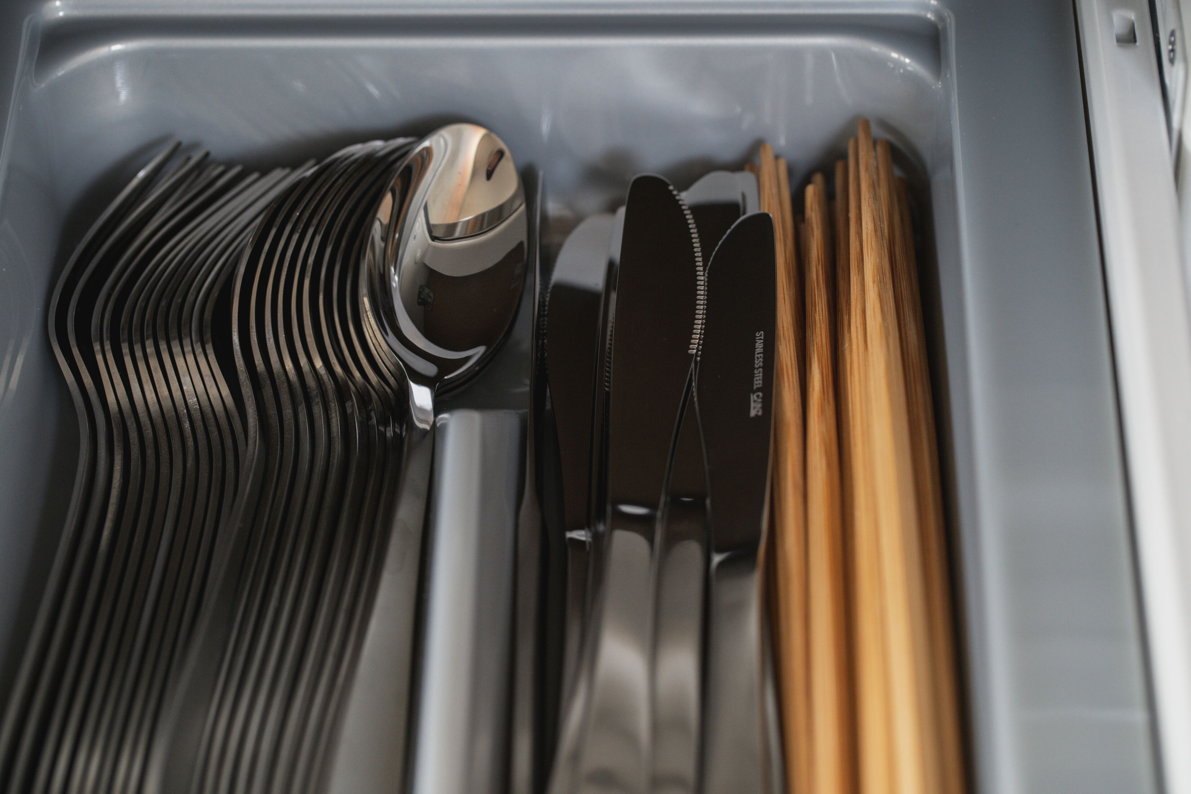 A drawer containing neatly organized utensils including forks, knives, and chopsticks.