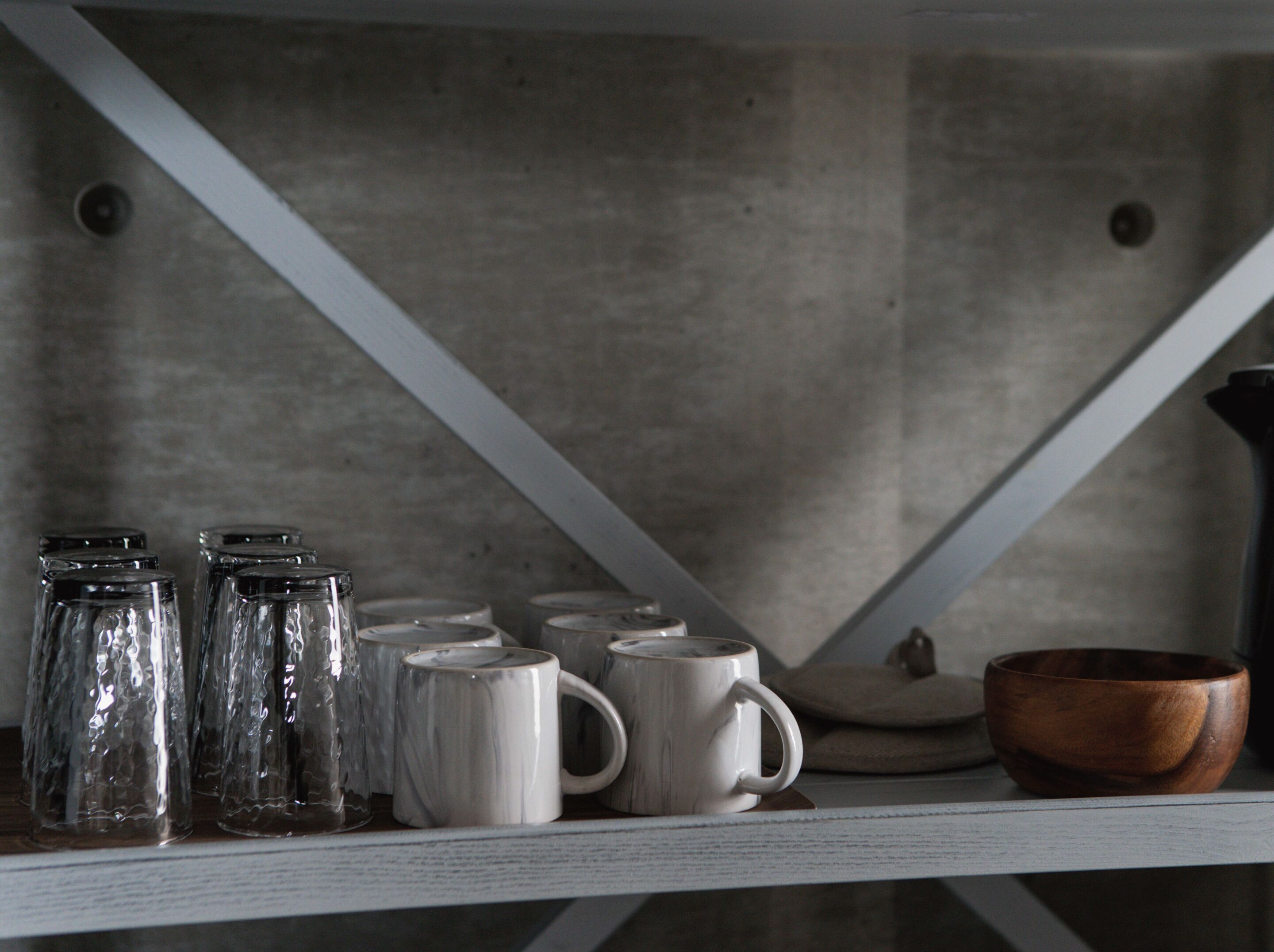 A shelf with various glass containers and ceramic mugs.