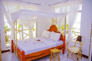 Relax in a serene space with a four-poster bed, white linens, and a comfortable stool.