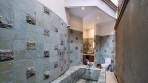 Un baño con paredes de piedra, una bañera, un inodoro y un lavamanos.