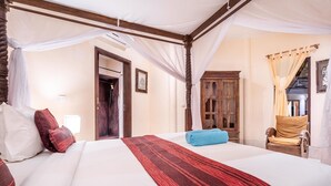 Una cama doble con una colcha a rayas roja y negra, cabecera de madera y dosel.