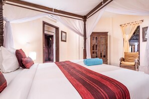 Una cama doble con una colcha a rayas roja y negra, cabecera de madera y dosel.
