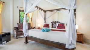 Una cama con dosel de cuatro postes, cortinas blancas, cabecera de madera y almohadas rojas y blancas.