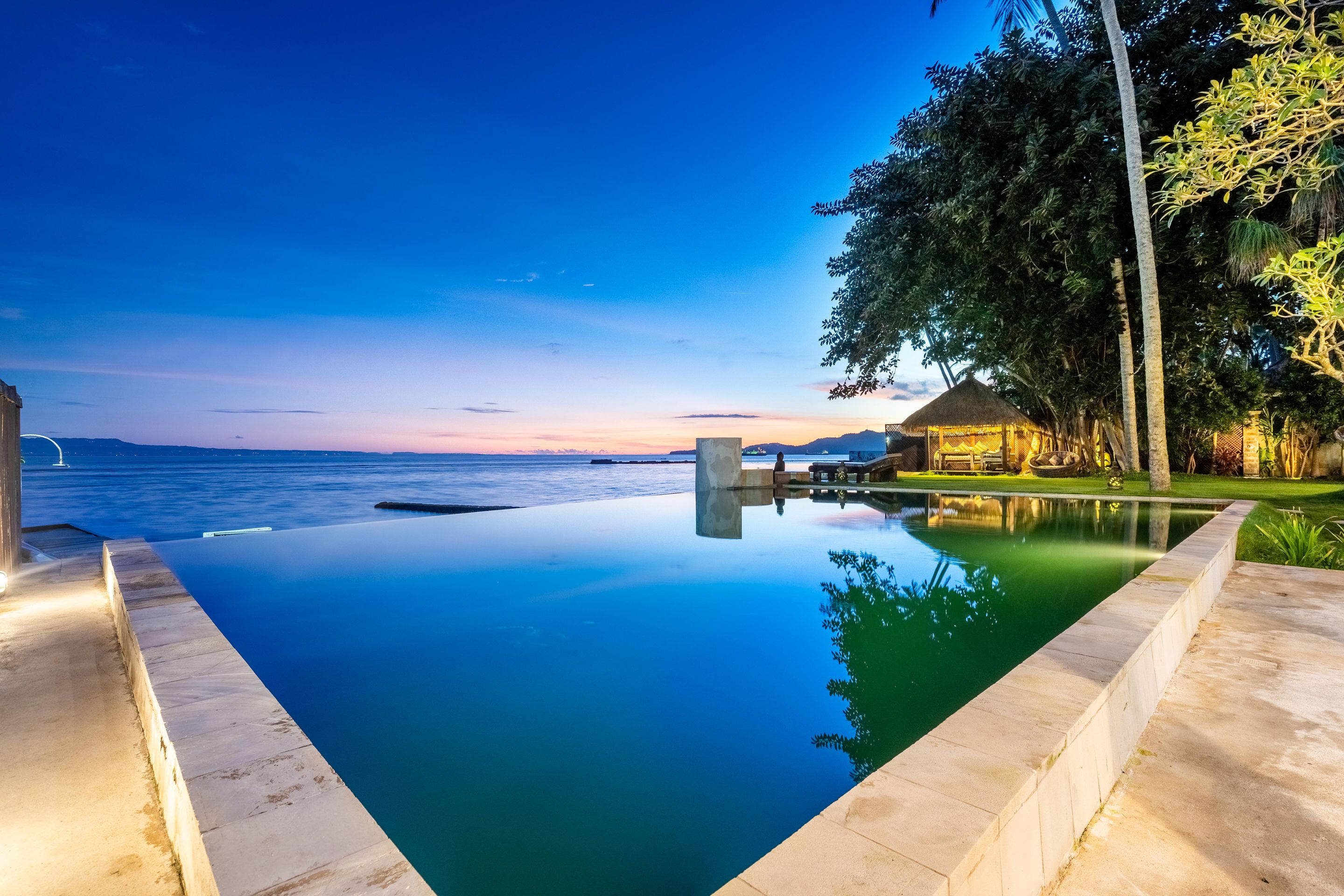 Una piscina infinita amb una vista clara de l'oceà i un capvespre al fons.