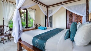 Ein Schlafzimmer mit einem Himmelsbett, einem Holzstuhl und einem Fenster mit Vorhängen.