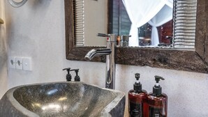 A bathroom with a large stone sink, a modern faucet, and two hand soap dispensers. - Double Room with Alley View | The Village of Angels Resort | Candidasa (Kabupaten Karangasem)