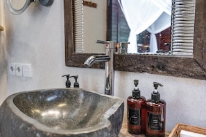 A bathroom with a large stone sink, a modern faucet, and two hand soap dispensers. - Double Room with Alley View | The Village of Angels Resort | Candidasa (Kabupaten Karangasem)