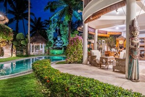A pool area with a statue, seating, and a thatched-roof structure. - Double Room with Alley View | The Village of Angels Resort | Candidasa (Kabupaten Karangasem)