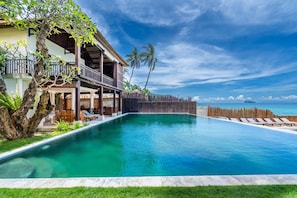 A resort with a swimming pool, lounge chairs, and a view of the ocean.