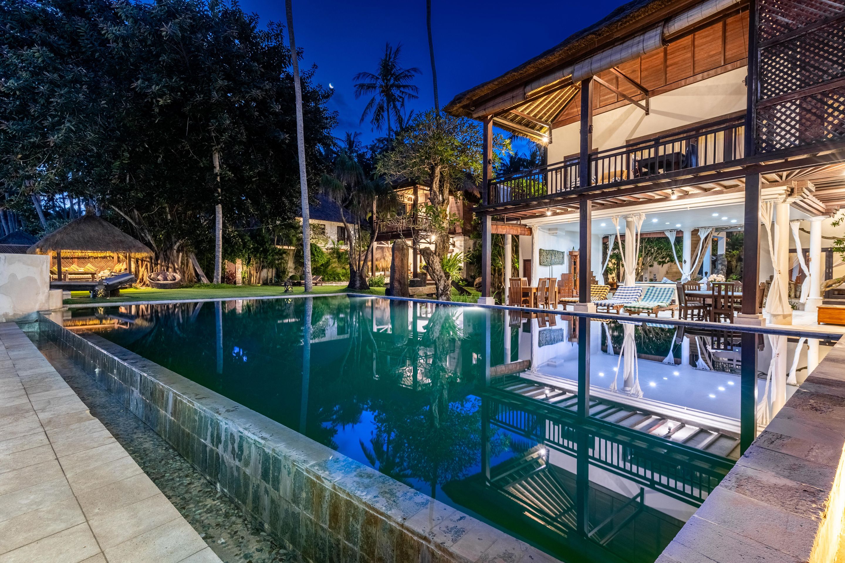 Una piscina con una vista despejada de los alrededores, incluyendo un edificio con balcón y zona de estar al aire libre.