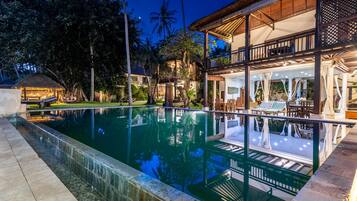 Una piscina con una vista despejada de los alrededores, incluyendo un edificio con balcón y zona de estar al aire libre.